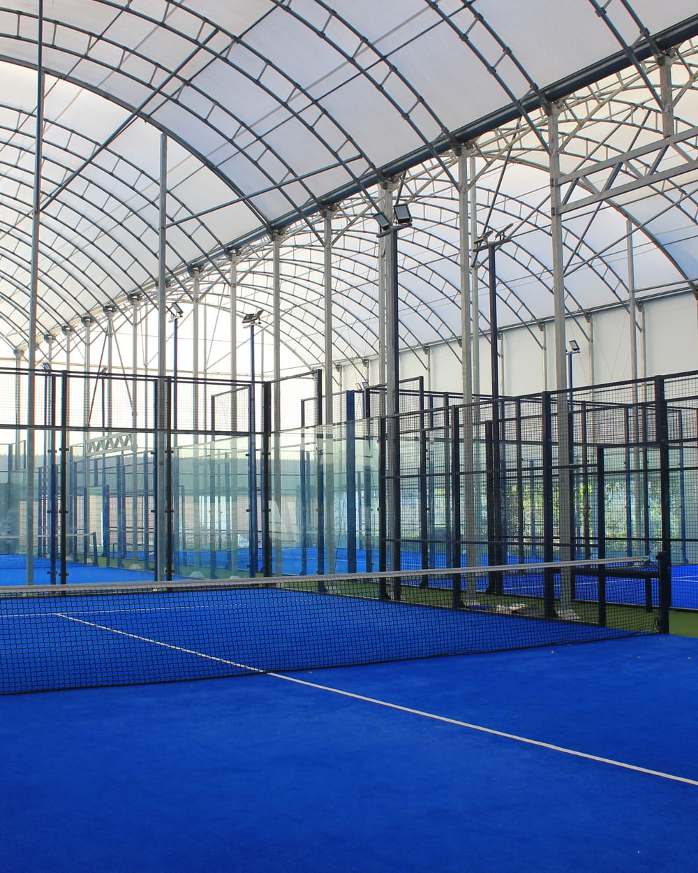 Pistes de padel bleues sous la structure couverte du domaine